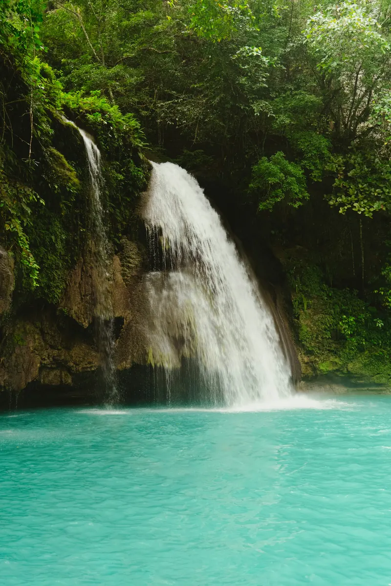 Kawasan Falls pouring into a turquoise pool surrounded by jungle in Badian
