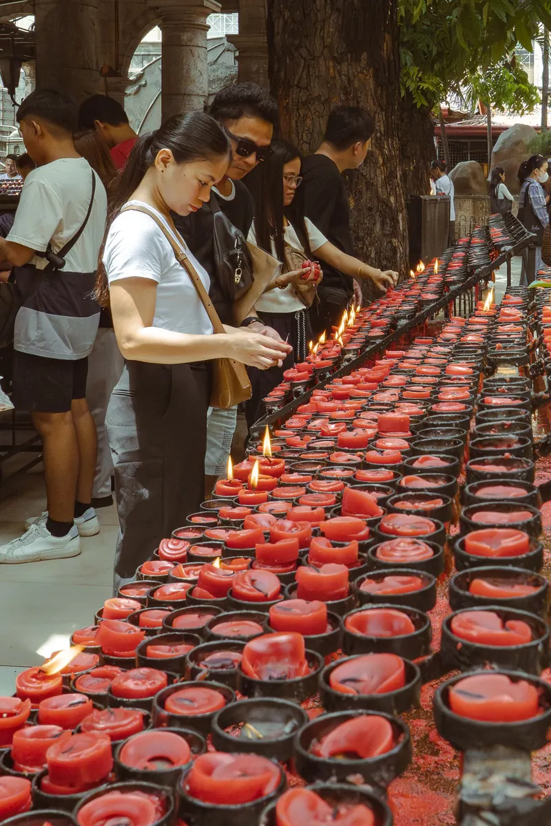 Visitors lighting rows of red candles at a religious site in Cebu City
