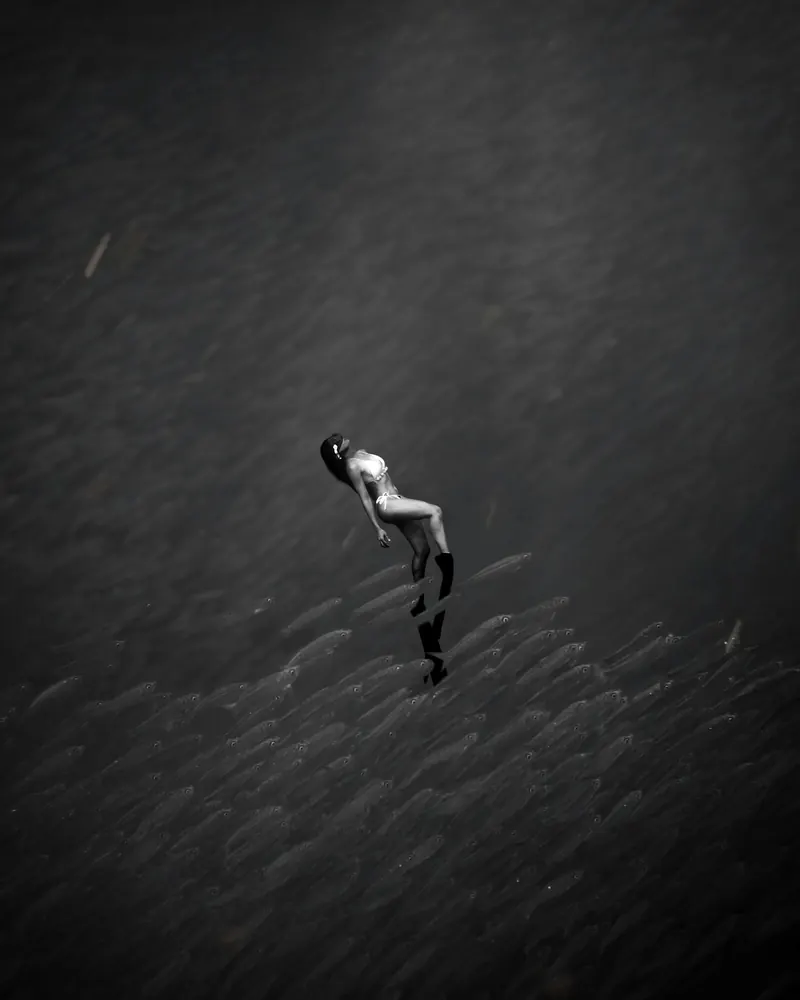 A freediver swimming above a huge school of sardines off Moalboal, black and white